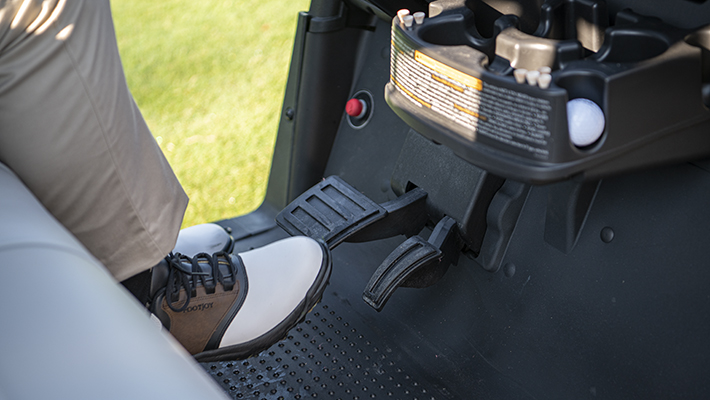 A foot preparing to press down on an E-Z-GO golf cart's brake pedal, powered by IntelliBrake.