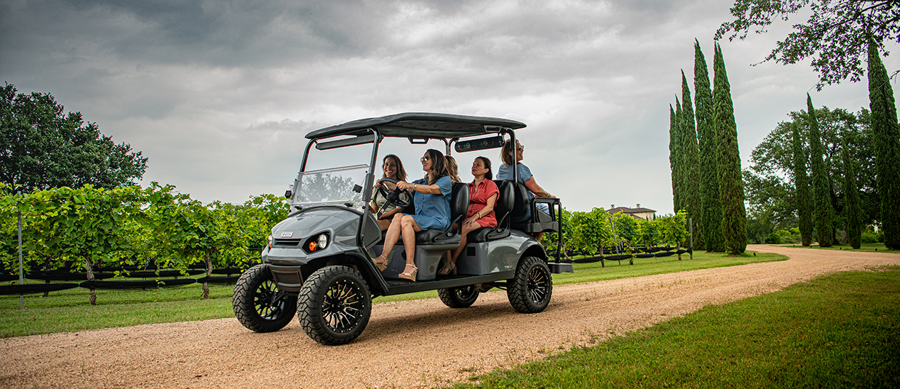 A family of six driving their E-Z-GO Express L6 down a gravel path.