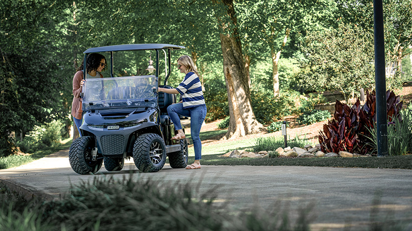 Two women board an E-Z-GO golf cart.