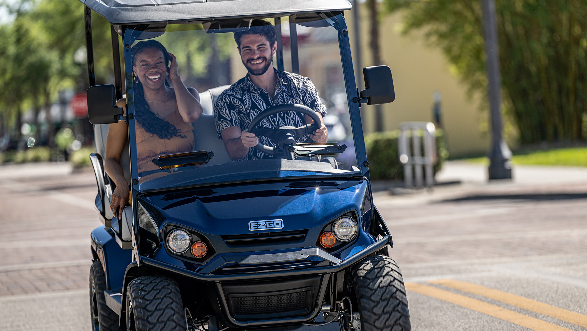 A couple driving an E-Z-GO golf cart.