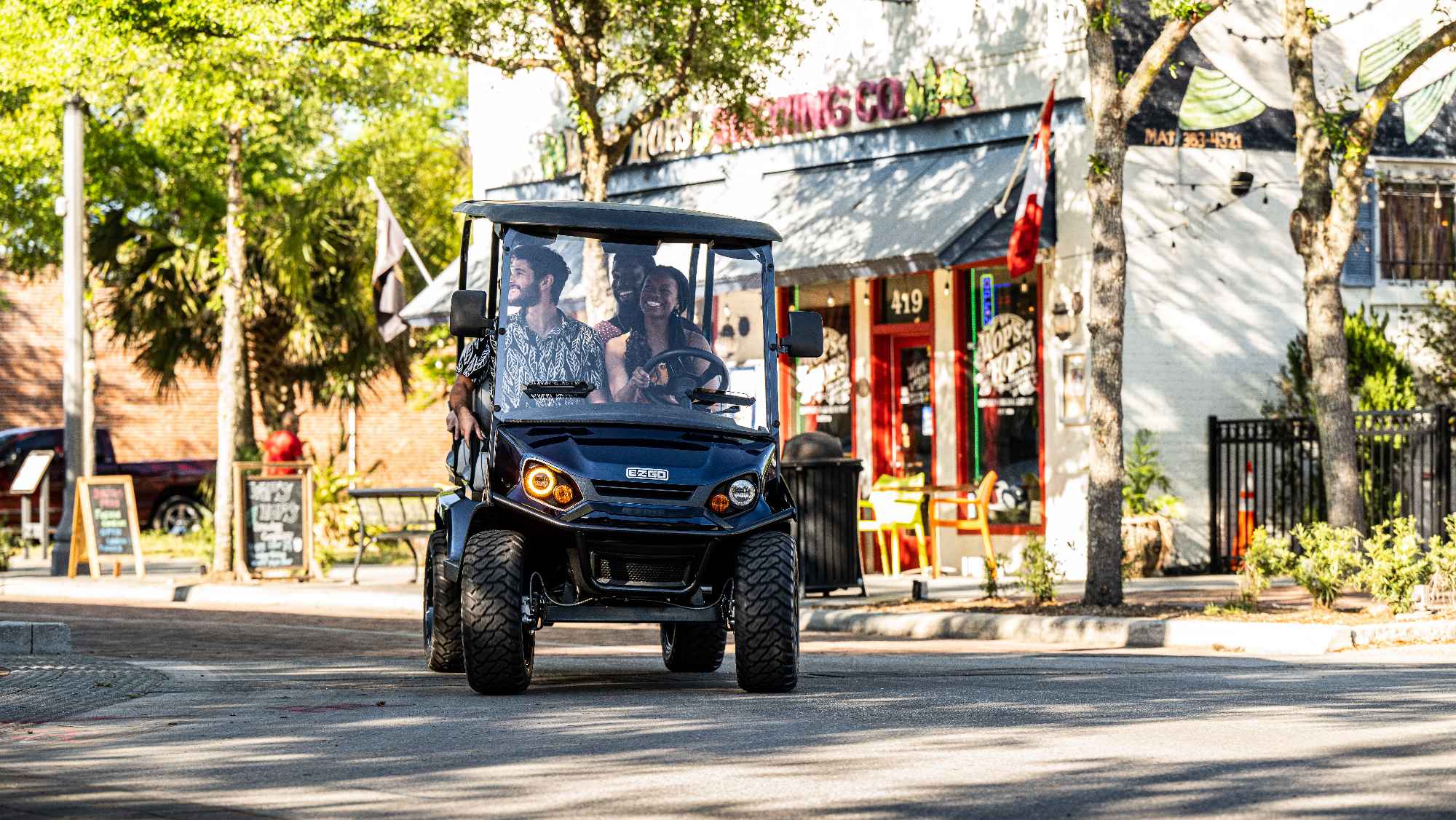 Three friends ride in an E-Z-GO LSV in a downtown shopping center.