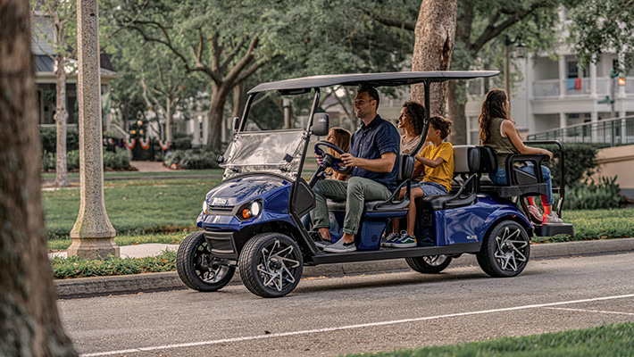 A family of six driving an E-Z-GO golf cart.