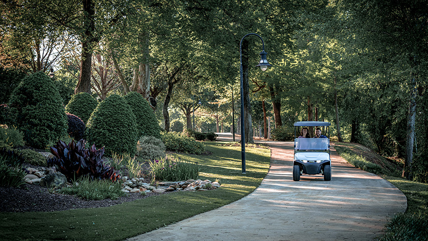 An E-Z-GO golf cart driving toward the camera down a street