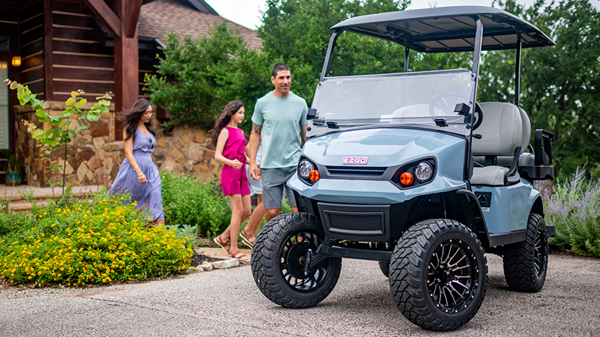 A family run toward their E-Z-GO golf cart for a ride.