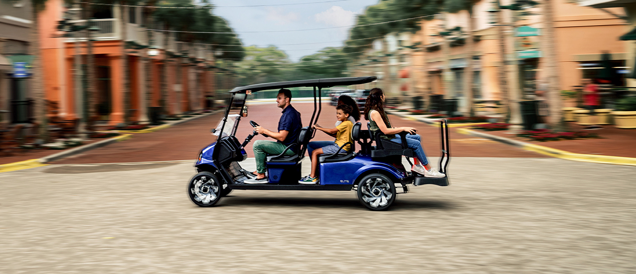 A family zooming down a road in their E-Z-GO Express S6 vehicle.