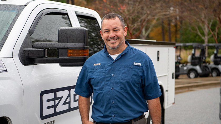 E-Z-GO technician standing in front of white maintenance truck