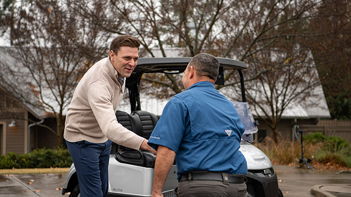 A customer shaking hands with an E-Z-GO service team member.