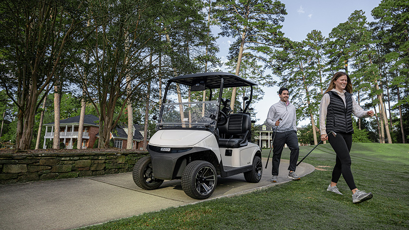 Two people getting ready to golf in front of their E-Z-GO vehicle