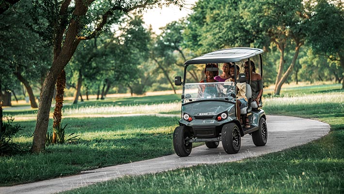 An E-Z-GO golf cart driving down a pathway