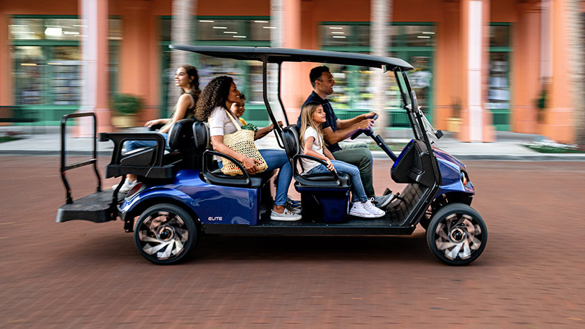 E-Z-GO passengers enjoy a speedy ride in a blue golf cart.