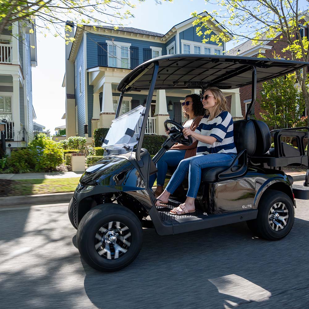 Two riders driving an E-Z-GO Freedom RXV down a neighborhood street.