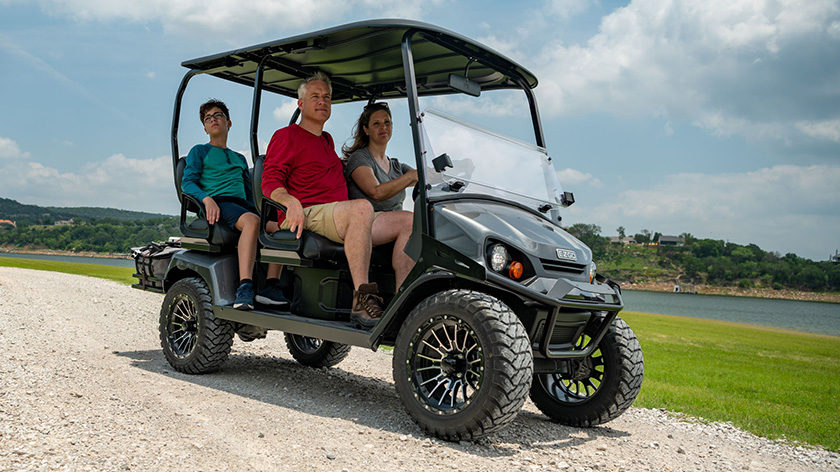 A family driving their E-Z-GO vehicle along a gravel path.