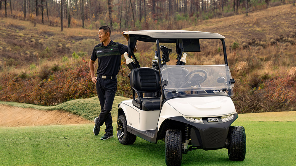 A golfer leans against an E-Z-GO golf cart.