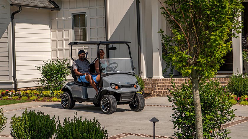 Happy homeowners smile while sitting in their new E-Z-GO golf cart.