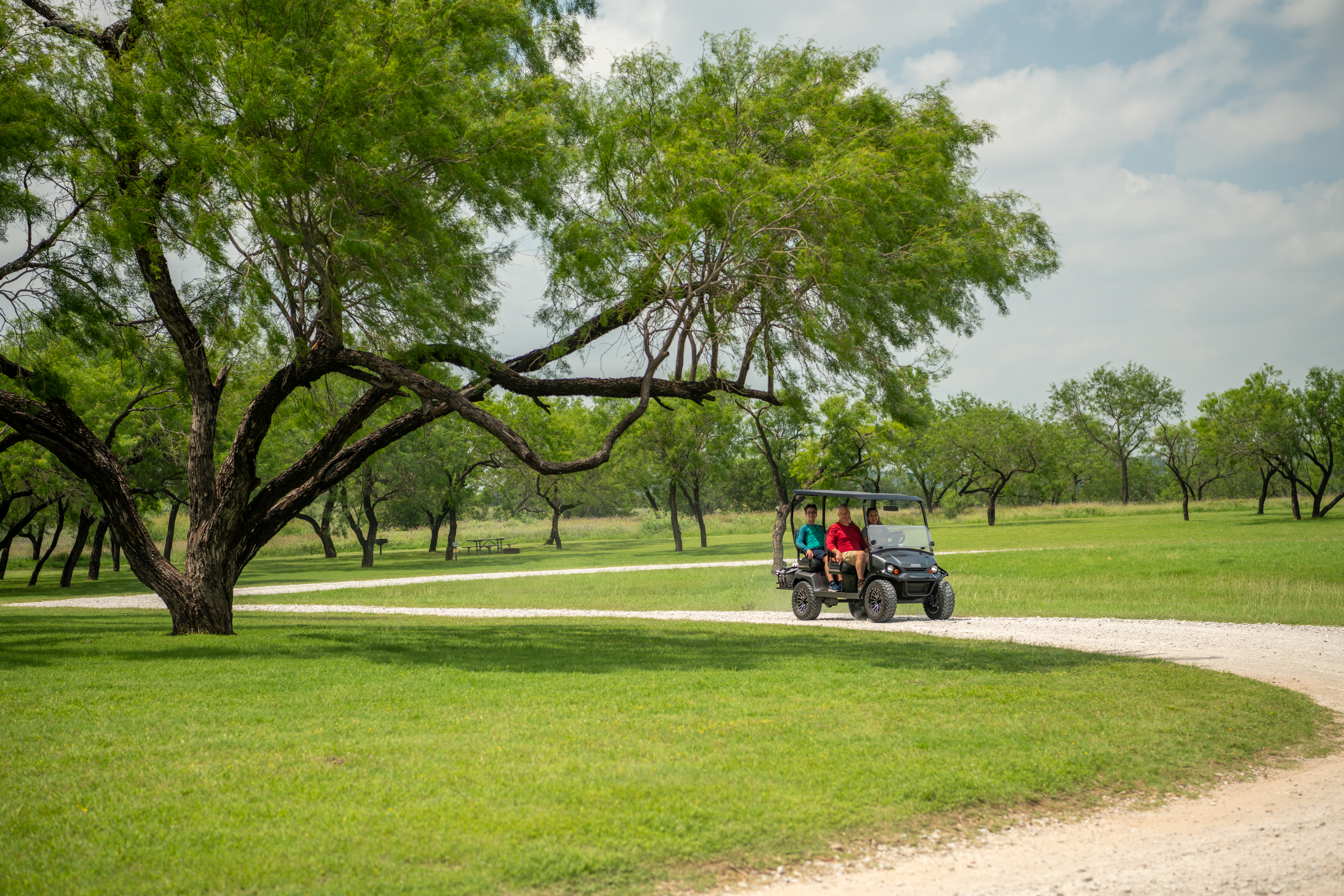 Family riding on E-Z-GO Liberty Golf Cart while camping