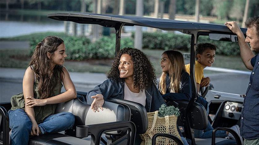 A group of riders sit and chat in an E-Z-GO Express S6 golf cart.