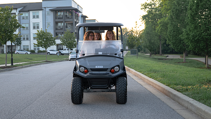Liberty driving on a road with an apartment in the background