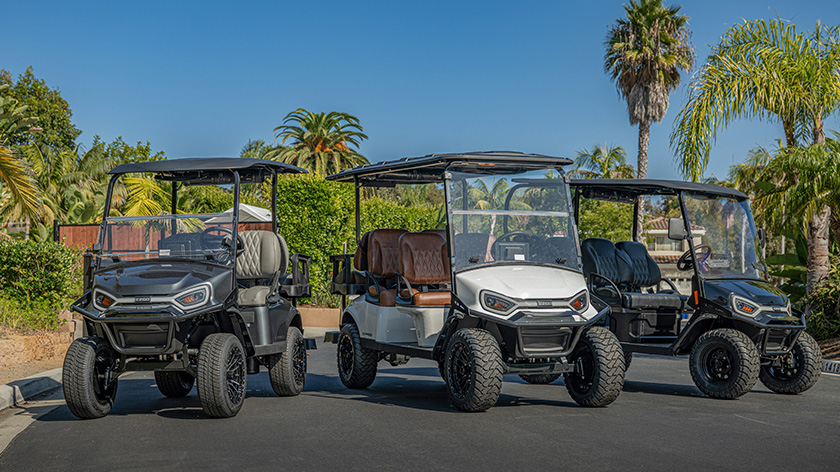 Group of Liberty LSV, Express 4 and Express 6 vehicles with LED headlights parking in a parking lot with palm trees in the back