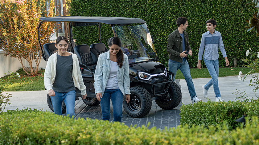 Liberty LSV parked in a driveway with family walking inside