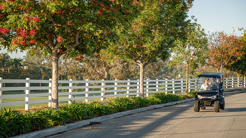 Liberty LSV driving in a neighborhood with a fence and trees in the background