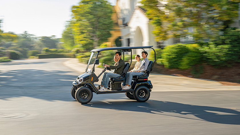 Four passengers riding in the four forward-facing seats in a neighborhood in a Liberty LSV