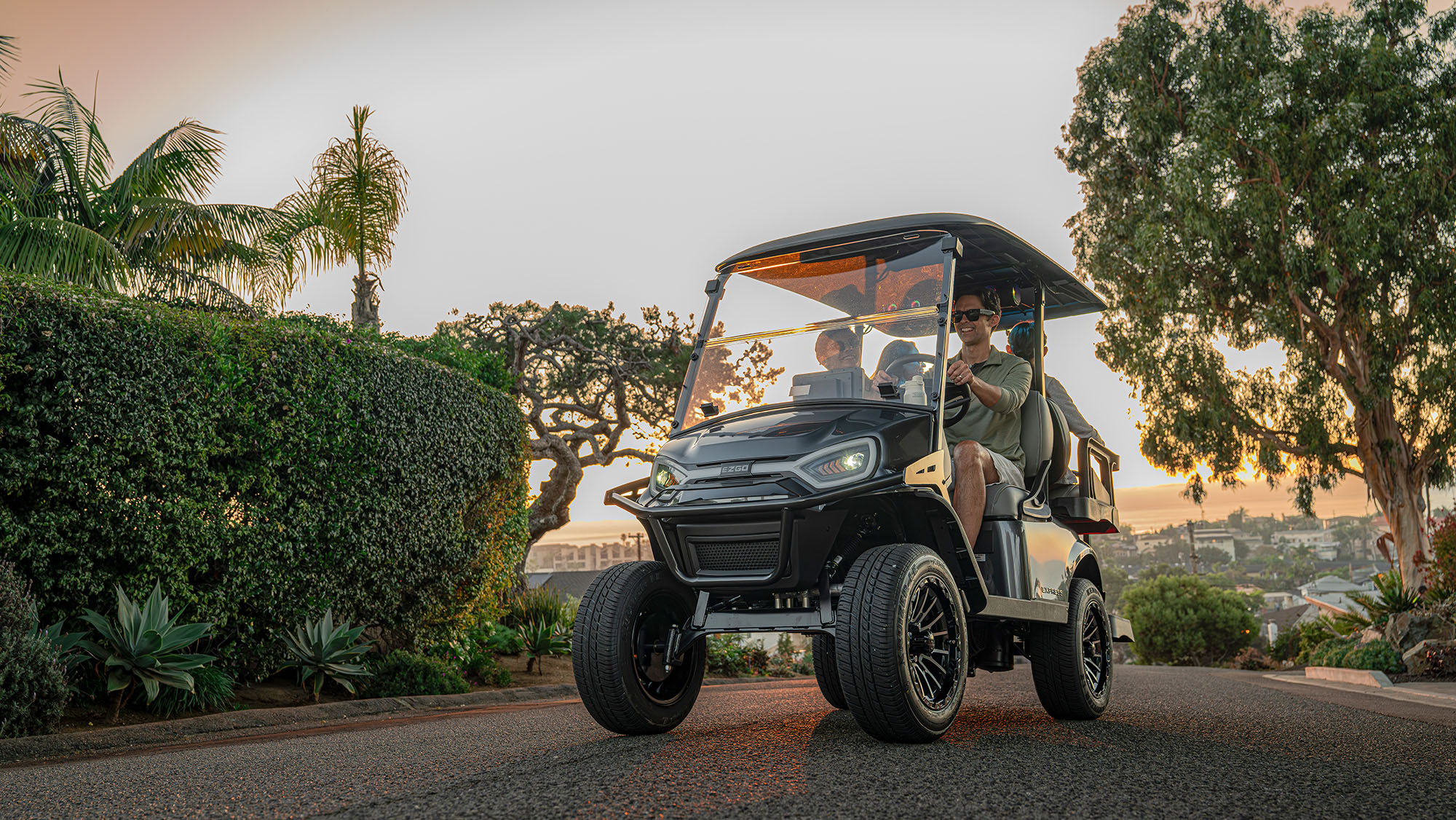 Express 4 driving in a neighborhood with a sunset, shrubs, and trees in the background