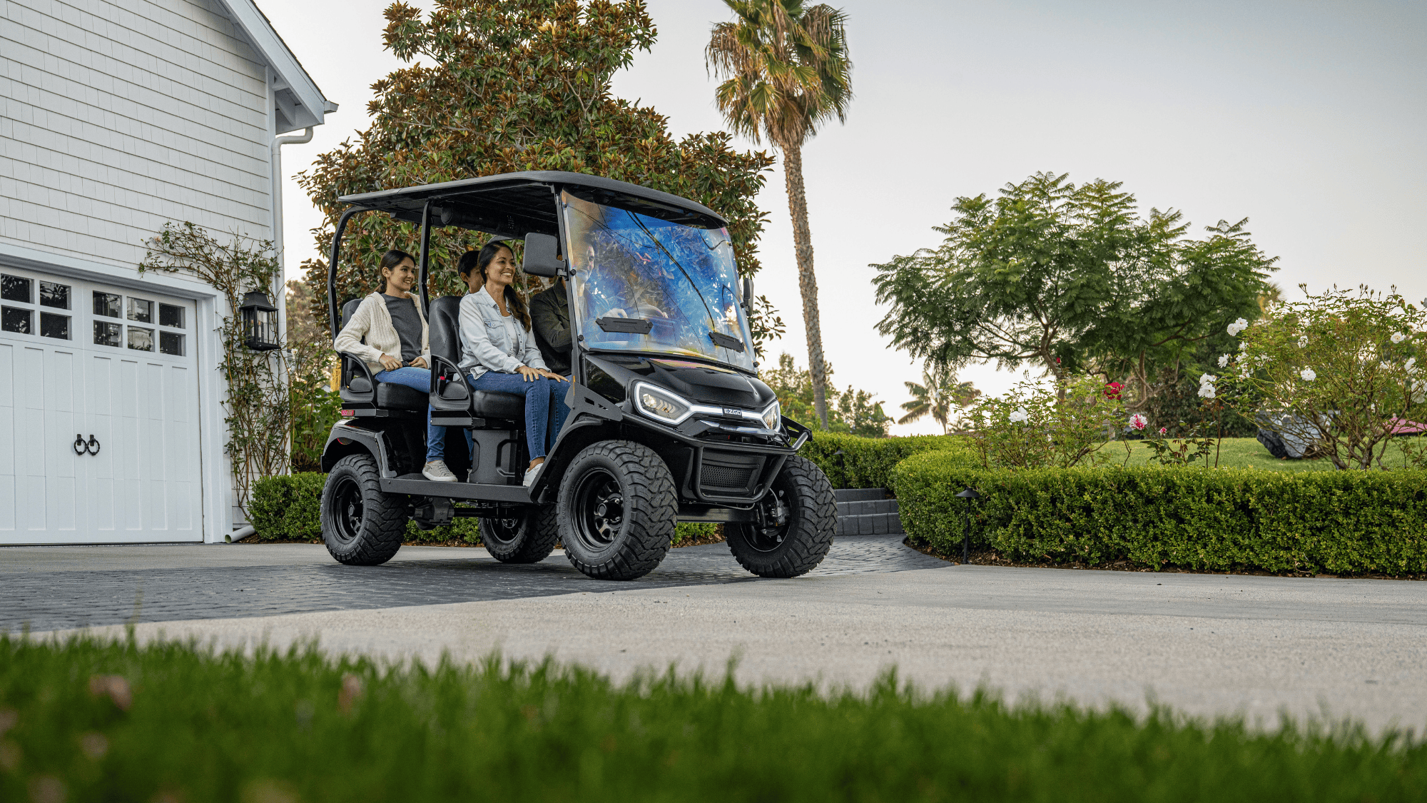 Liberty LSV in front of a house parked in the driveway with family of 4 in the cart.