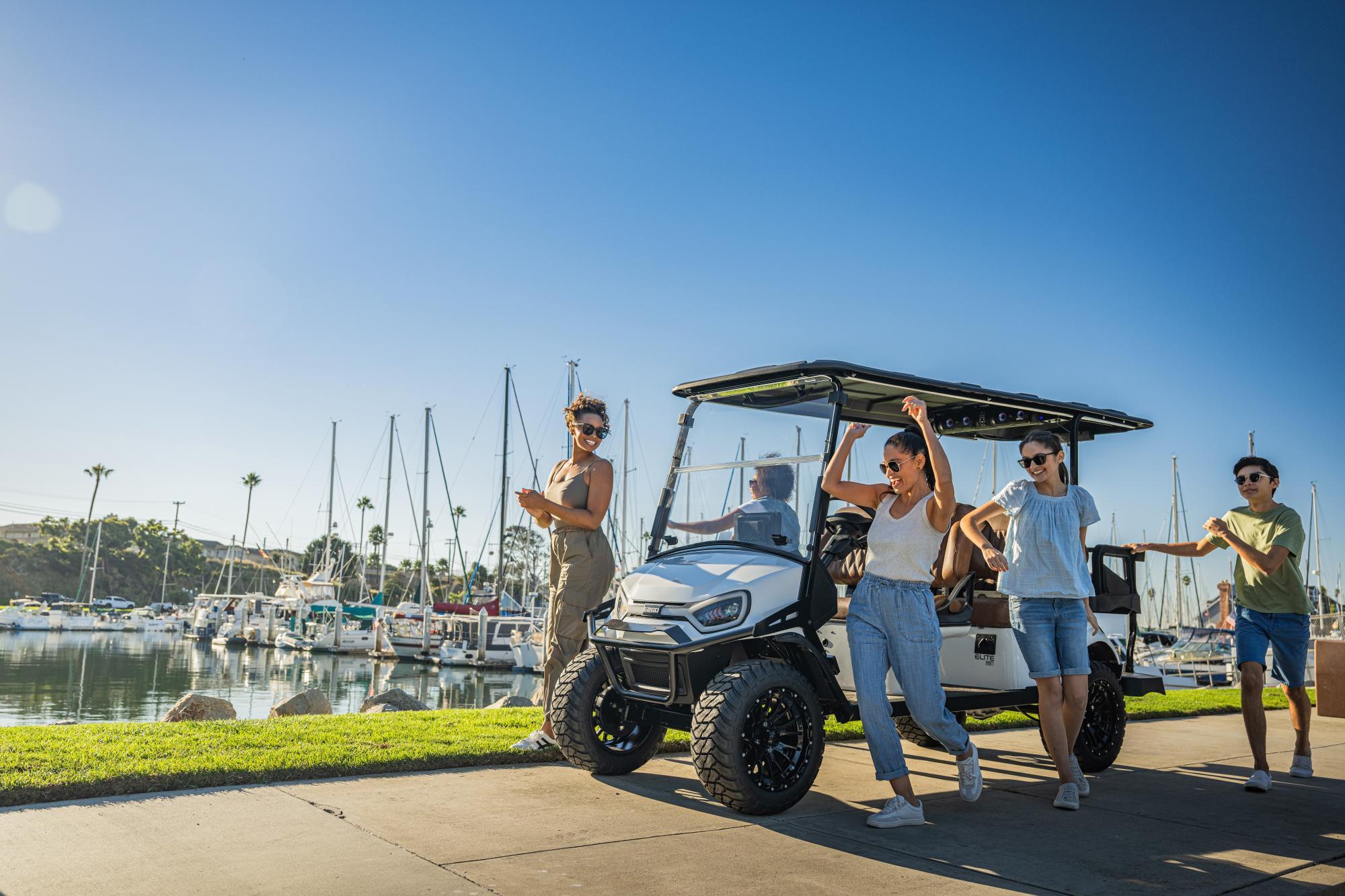 E-Z-GO Express 6 electric golf cart with a family of 6 walking around it