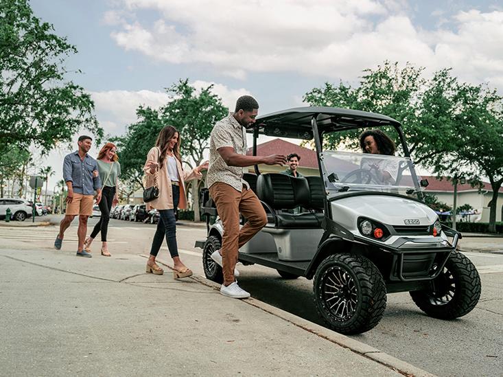 A group of friends getting aboard an E-Z-GO golf cart.